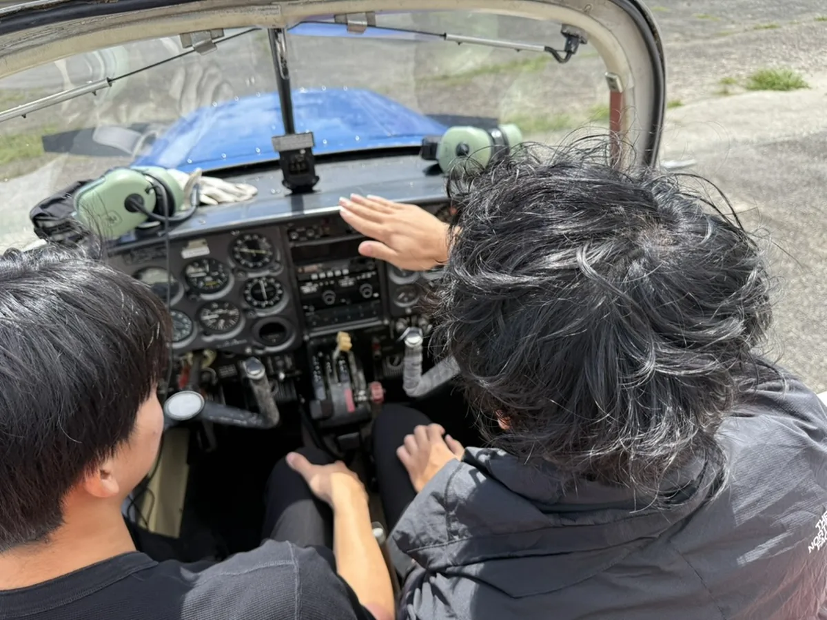 エアロスバルJA3689のコックピットで計器盤を指しながら説明を受ける訓練生