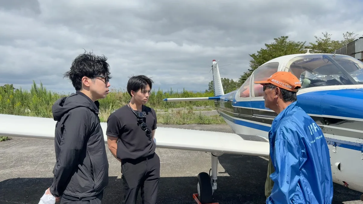 阿蘇の場外離着陸場でエアロスバルJA3689を前に説明を受ける訓練生とスタッフ