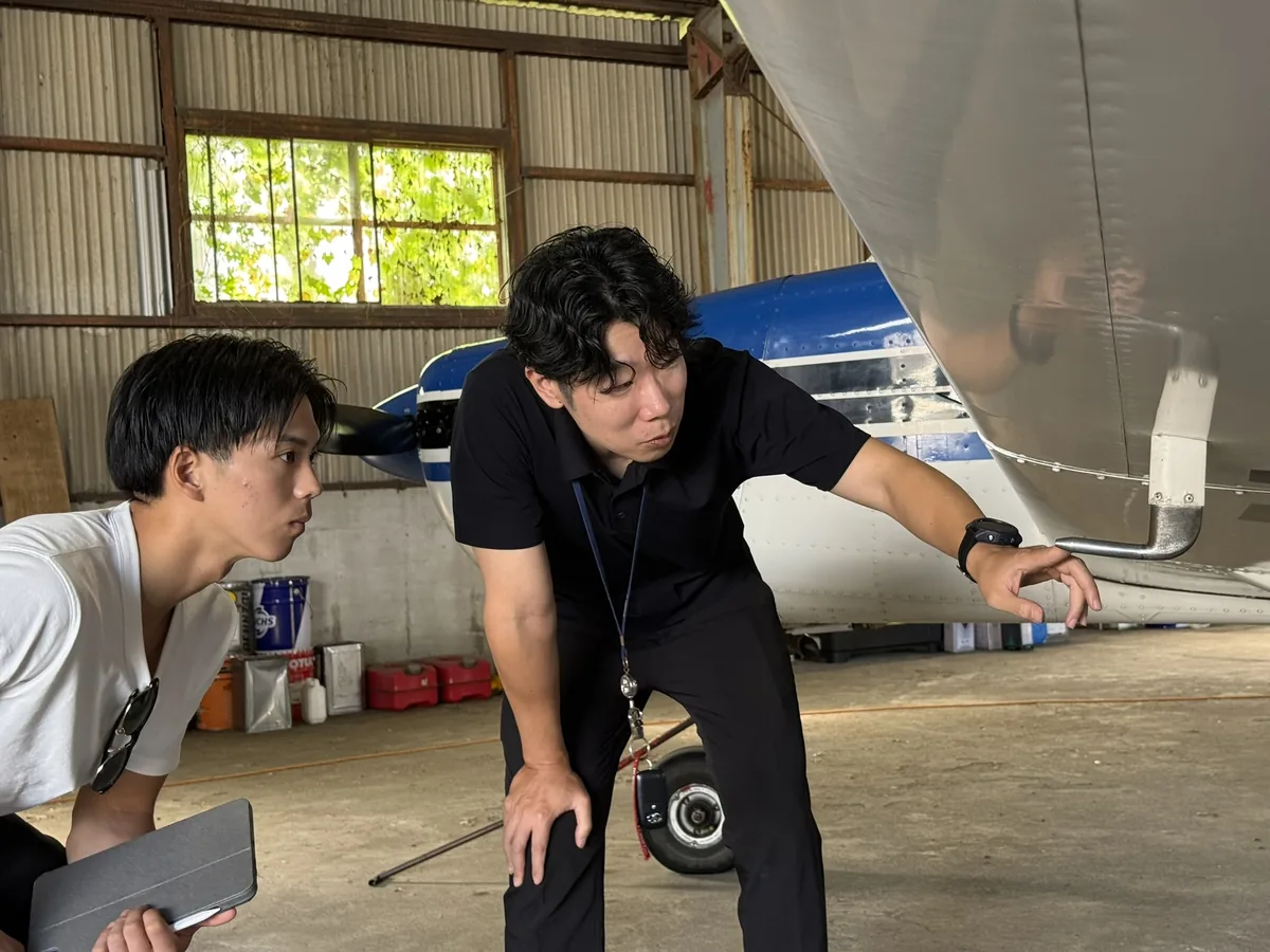 エアロスバルJA3689の尾翼付近を指しながら構造を説明する様子