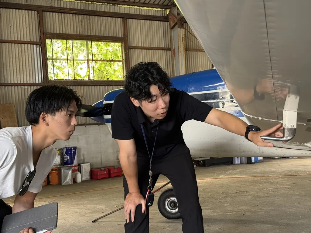 機体の構造を指しながら説明を受ける様子